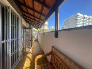 a balcony with a wooden bench and large windows at gaivotas com ar condicionado in Guarapari