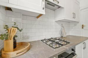 a kitchen with white cabinets and a stove top oven at Wembley Hububb Stay in London