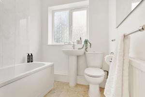 a white bathroom with a toilet and a sink at Wembley Hububb Stay in London
