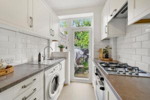 a white kitchen with a sink and a stove at Wembley Hububb Stay in London