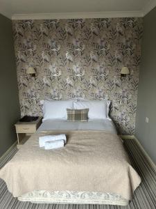 a bedroom with a large bed with a floral wallpaper at The Ardingly Inn in Ardingly