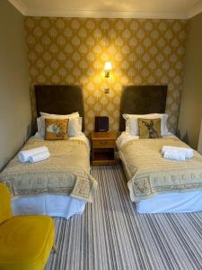 um quarto de hotel com duas camas e uma cadeira em The Ardingly Inn em Ardingly