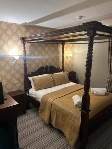 The Ardingly Inn في أردينغلي: غرفة نوم مع سرير مظلة في غرفة