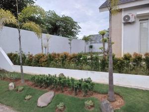 un jardin avec une clôture, des arbres et des rochers dans l'établissement Rumah Sakura Jonggol, à Jonggol