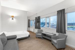 um quarto de hospital com uma cama, cadeiras e janelas em Hótel Vellir em Hafnarfjördur