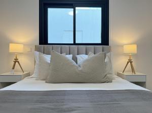 łóżko z białymi poduszkami i okno w sypialni w obiekcie Phaedrus Living: White Hills Suites City View w mieście Aglantzia