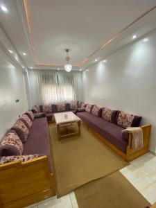 ein Wohnzimmer mit einem großen Sofa und einem Tisch in der Unterkunft Appartement avec suite parentale in Mohammedia