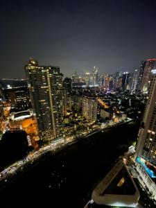 The Serene Escape Rockwell Makati City View 1BR في مانيلا: أفق المدينة في الليل مع النهر والمباني