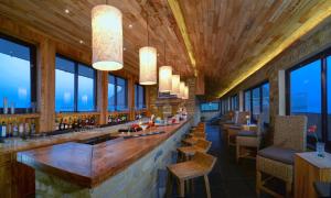 a restaurant with a bar with chairs and windows at Sarangkot Mountain Lodge in Pokhara