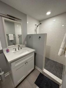 La salle de bains blanche est pourvue d'un lavabo et d'un miroir. dans l'établissement Elegant 1 Bdr-Montrose_ Siena @The Italian Plaza, à Houston