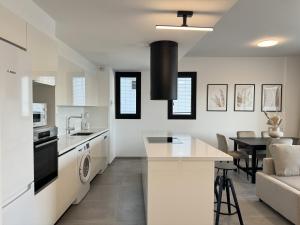a kitchen and living room with white appliances and a table at Phaedrus Living: White Hills Suites City View in Aglantzia