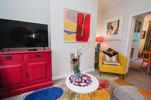 uma sala de estar com um armário vermelho e uma televisão em Hoole House em Chester