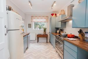 uma cozinha com armários azuis e um frigorífico branco em Hoole House em Chester