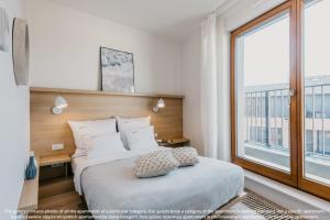 a bedroom with a bed and a large window at EXCLUSIVE Aparthotel Kraków Browar Lubicz in Krakow