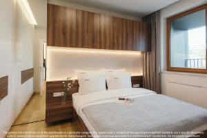 1 dormitorio con 1 cama blanca grande y ventana en EXCLUSIVE Aparthotel Kraków Browar Lubicz en Cracovia