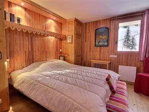 Un dormitorio con una cama grande con paredes de madera. en Chalet chaleureux proche des pistes, balcon et WiFi - FR-1-455-227, en La Plagne Tarentaise