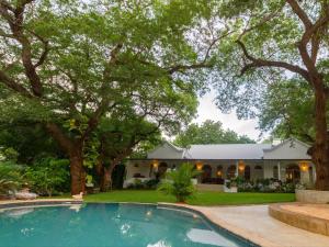 una casa con piscina frente a una casa en The Courtney Lodge en Victoria Falls