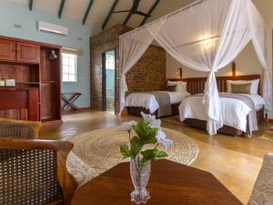 un dormitorio con 2 camas y una mesa con un jarrón de flores en The Courtney Lodge en Victoria Falls