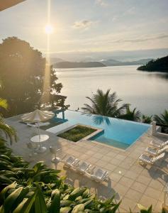 a swimming pool with chairs and a view of the water at Oásis Beach House in Angra dos Reis