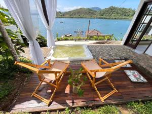 eine Terrasse mit 2 Stühlen und einem Whirlpool in der Unterkunft Oásis Beach House in Angra dos Reis