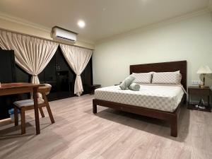 1 dormitorio con cama, escritorio y piano en Bao Sheng Durian Farm, en Balik Pulau