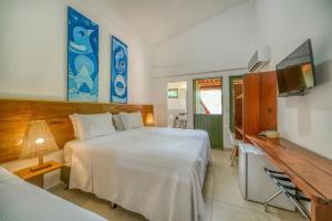 a bedroom with a bed and a desk and a television at Pousada Rota Ecológica in Pôrto de Pedras
