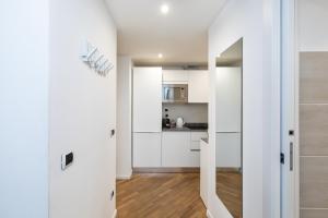 une cuisine avec des placards blancs et une porte menant à une chambre dans l'établissement MagnoliaApartments - 5 Nirone Center, à Milan