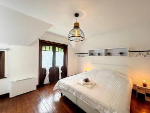 een slaapkamer met een wit bed en een hanglamp bij Maison Ker Armor - De Panne in De Panne