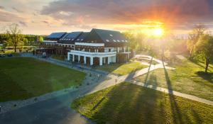 an aerial view of a building with the sun setting at Natural Hotel w Rezerwacie z Plażą Na Wyspie in Ostróda