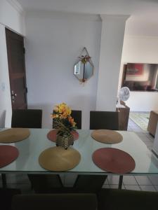 a dining room table with a vase of flowers on it at Apartamento 3 quartos beira mar Intermares-Cabedelo VALOR DA TAXA DE LIMPEZA E DO AR CONDICIONADO COBRADO À PARTE in Cabedelo