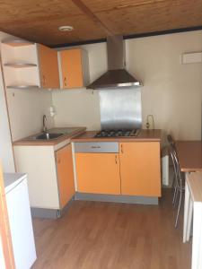 uma cozinha com armários laranja e branco e uma mesa em Orbitur Ilha de Armona em Olhão