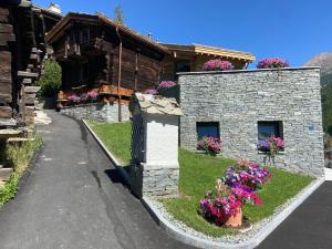 a stone building with flowers in front of it at Chalet Coral und Zermatter Stadel in Zermatt