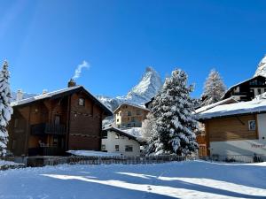 un village enneigé avec une montagne en arrière-plan dans l'établissement Chalet Coral und Zermatter Stadel, à Zermatt