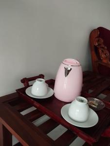 a table with two plates and a pink tea pot at Rose Dale Homestay Ella in Ella