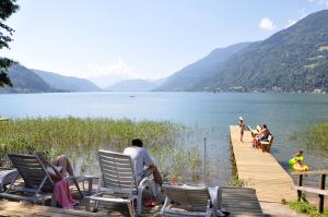 a group of people sitting on a dock near a lake at Appartementhaus Karantanien am Ossiacher See in Ossiach