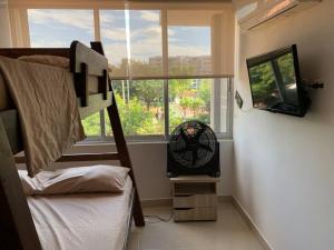 um quarto com um beliche, uma ventoinha e uma janela em apartamento en peñazul aldea em Ricaurte