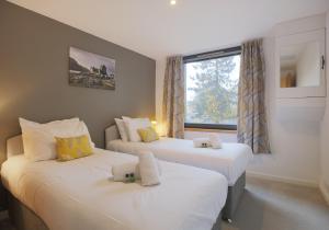 Duas camas num pequeno quarto com uma janela em The East London Residence em Edimburgo
