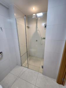 La salle de bains est pourvue d'une douche avec une porte en verre. dans l'établissement ECOSUMMER FLATS TAMBAÚ - Flat na praia de Tambaú, à João Pessoa