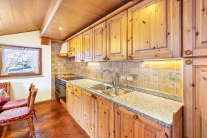 a kitchen with wooden cabinets and a sink at Majon Garneté Buffaure 5 in Pozza di Fassa
