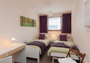 Pokój z 2 łóżkami i biurkiem w obiekcie Logie Green Road Apartment w Edynburgu