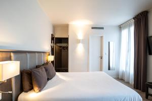 a bedroom with a large white bed and a window at Hotel de Flore - Montmartre in Paris