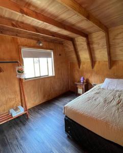 ein Schlafzimmer mit einem Bett in einem Zimmer mit einem Fenster in der Unterkunft Cabaña Pumol in Futrono