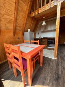 einen Holztisch und Stühle in der Küche in der Unterkunft Cabaña Pumol in Futrono