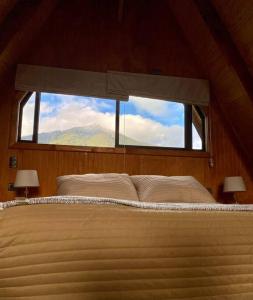 1 dormitorio con 1 cama grande y ventana en Cabaña Pumol, en Futrono