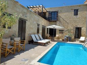 a pool with chairs and an umbrella next to a building at Niovi House in Tochni