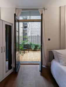 ロンドンにあるCasa lujosa de 4 habitaciones cerca un minuto de la estaciónのベッドルーム1室(ベッド1台付)、バルコニーへのスライドドアが備わります。