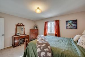 Schlafzimmer mit einem Bett, einer Kommode und einem Spiegel in der Unterkunft Loveland Home with Private Hot Tub and Wood Fireplace! in Loveland