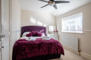 a bedroom with a purple bed and a ceiling fan at Ashbourne House - Close to Central Woking in Woking