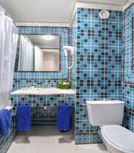 a blue tiled bathroom with a toilet and a sink at El Oumara Hotel in Tunis