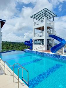 EliJosh Resort and Events Place في Silang: مسبح بزحليقة مائية امام مبنى